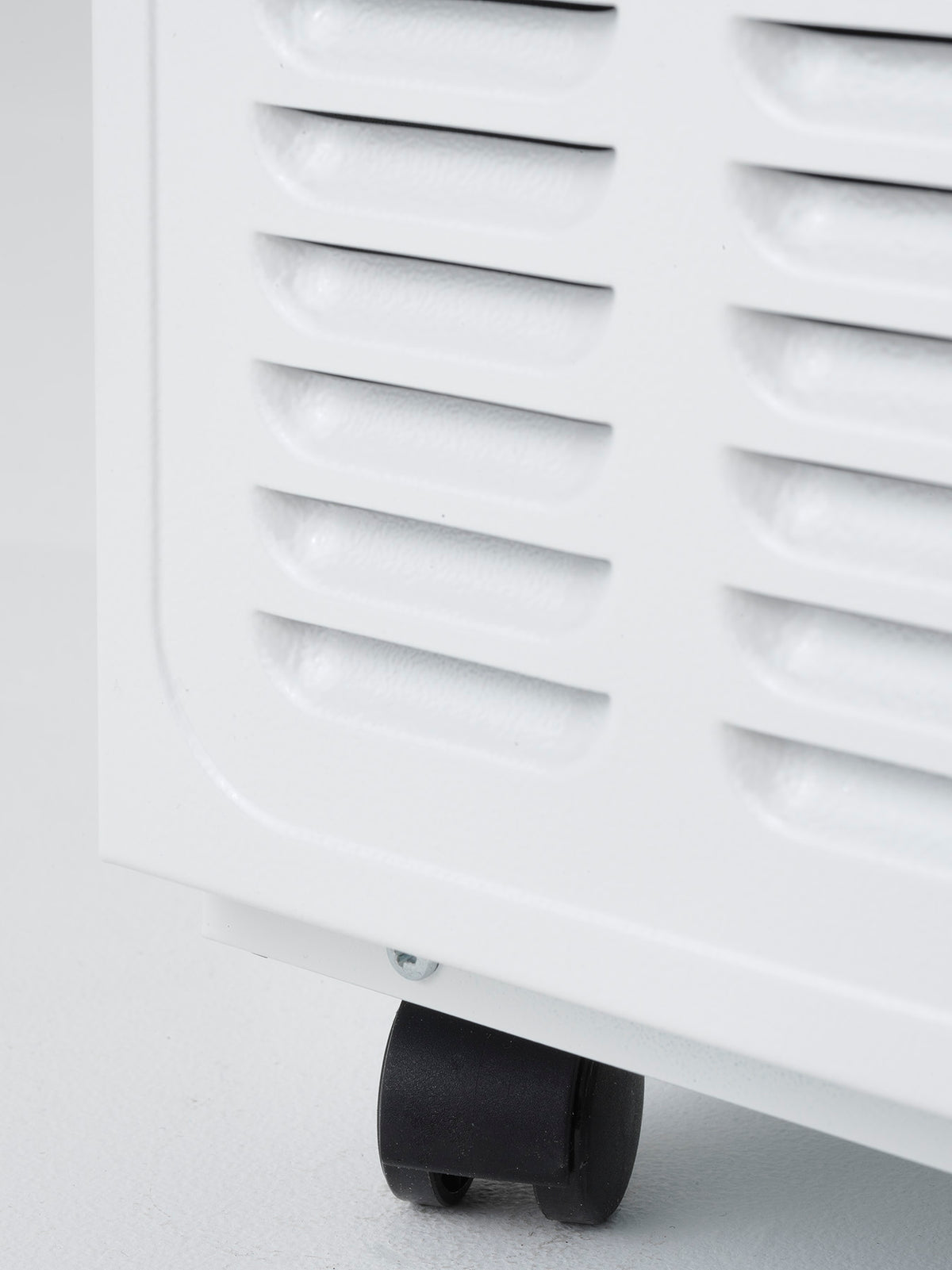 Close-up of a white dehumidifier with a black wheel on a light gray background