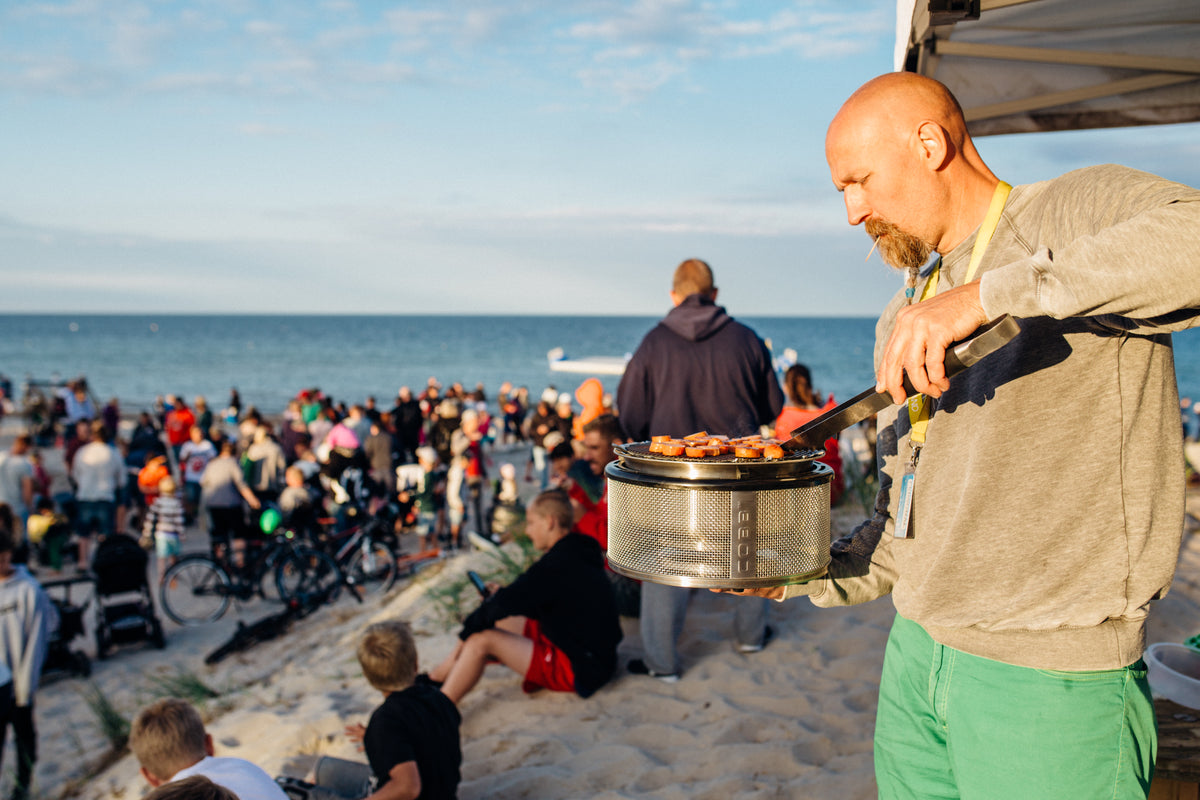 Friends enjoying outdoor cooking with a COBB grill at the beach